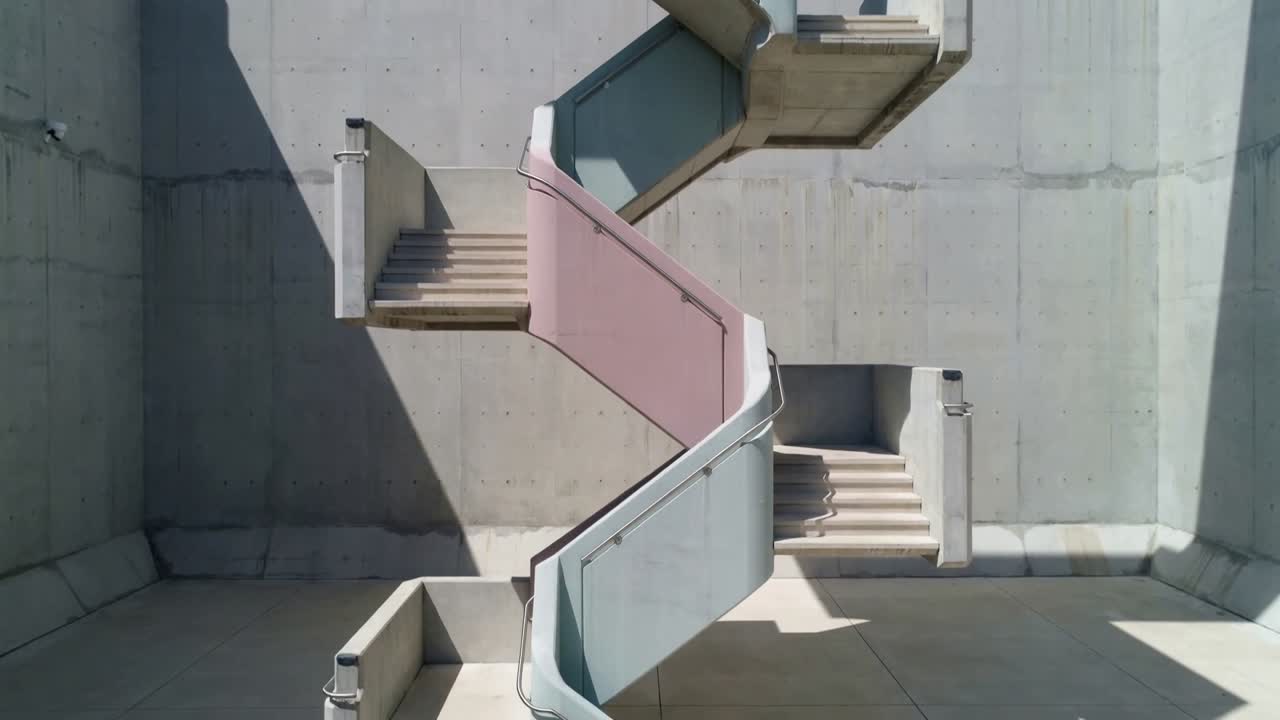 La telecamera si sposta verso il basso rivelando una scala a zig-zag, pannelli rosa e azzurri con ombre in movimento per il design.