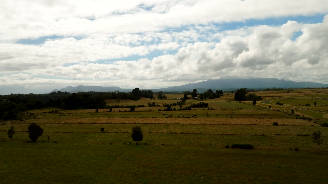 Agricultural fields near Puerto Varas, vast rural landscape, cloudy sky, southern Chile countryside. Aerial forward