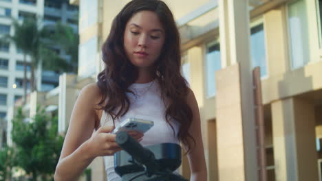 asian lady rent scooter pay using smartphone close up. woman take electric bike