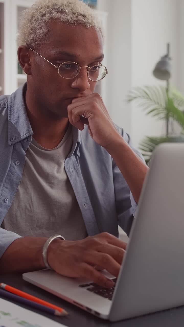 Young smart african american man journalist uses laptop sits at desk in office