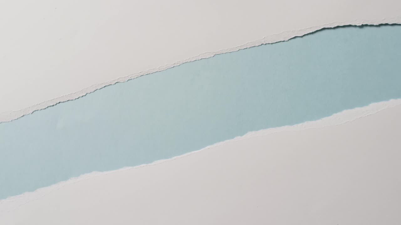 Video of close up of torn pieces of white paper on blue background