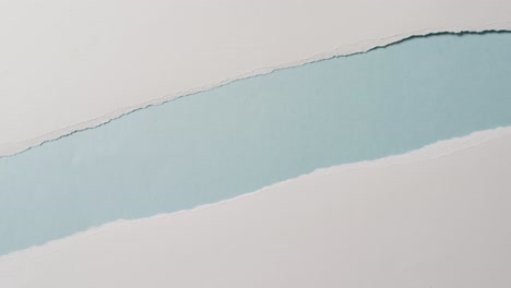 video of close up of torn pieces of white paper on blue background