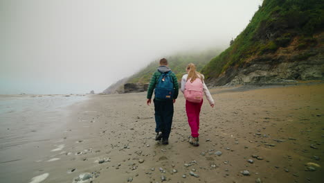 couple walking on a misty beach with cliffs