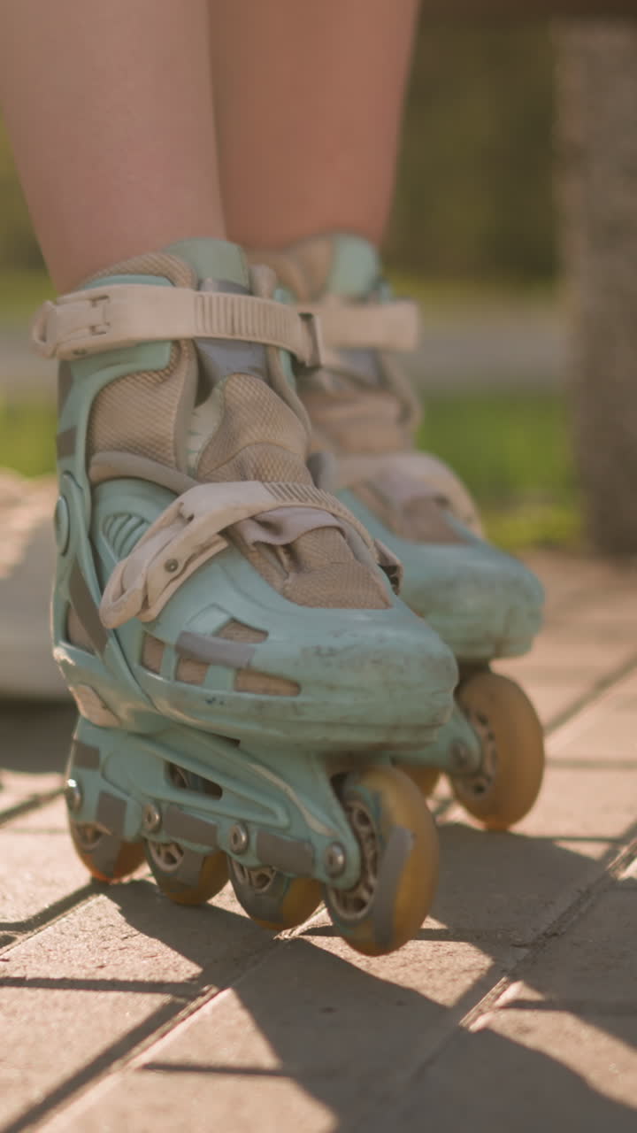 Leg view of lady in roller skates moving back and forth on paved ground with sneakers slightly blurred behind, sunlight casting shadows, surrounded by greenery