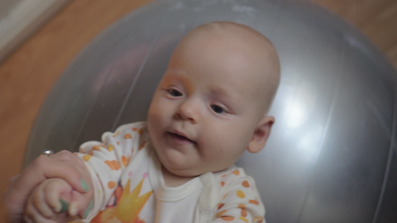 큰 은색 체조 공 에 누워 있는 아기 소녀