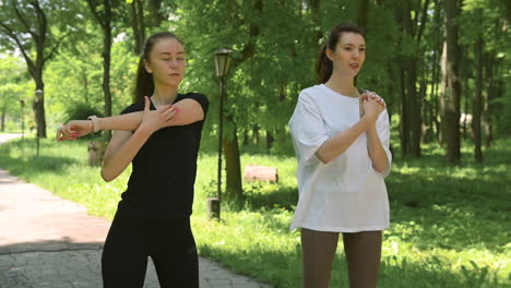 dos felices corredores de chicas guapas calentándose y estirándose en el parque antes de correr