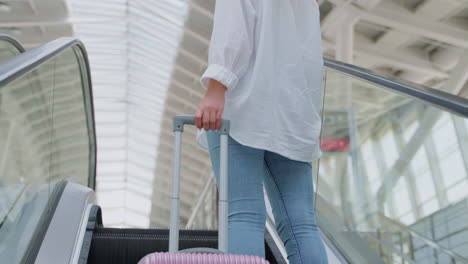 woman traveling on an airport escalator with luggage