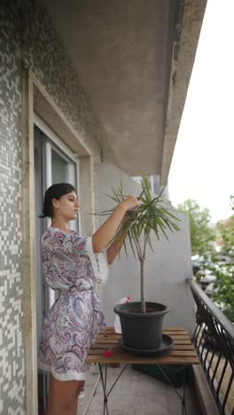 woman taking care of a houseplant on a balcony