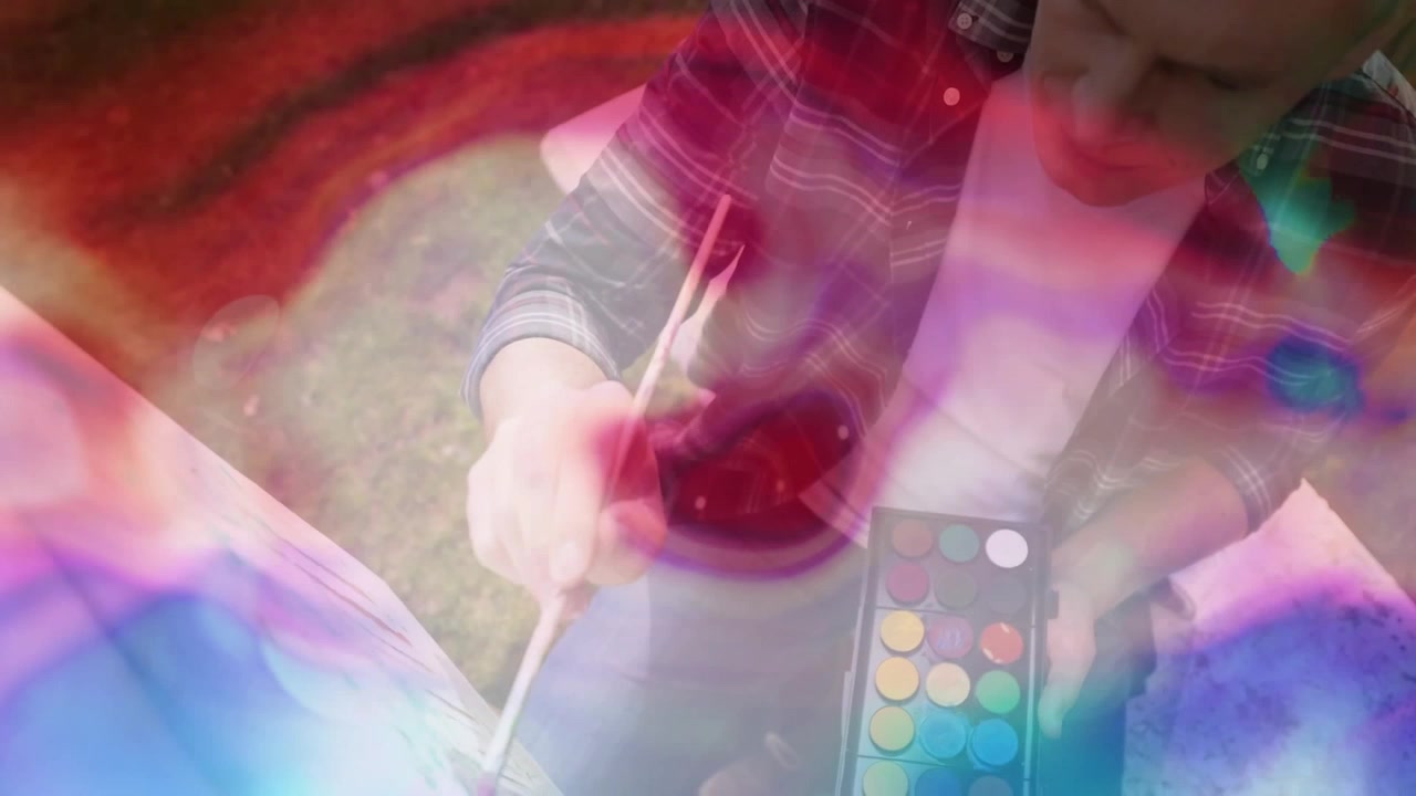 Hombre maduro sumergiendo el pincel en la paleta de pintura y creando arte mientras una superposición ondulada se desplaza