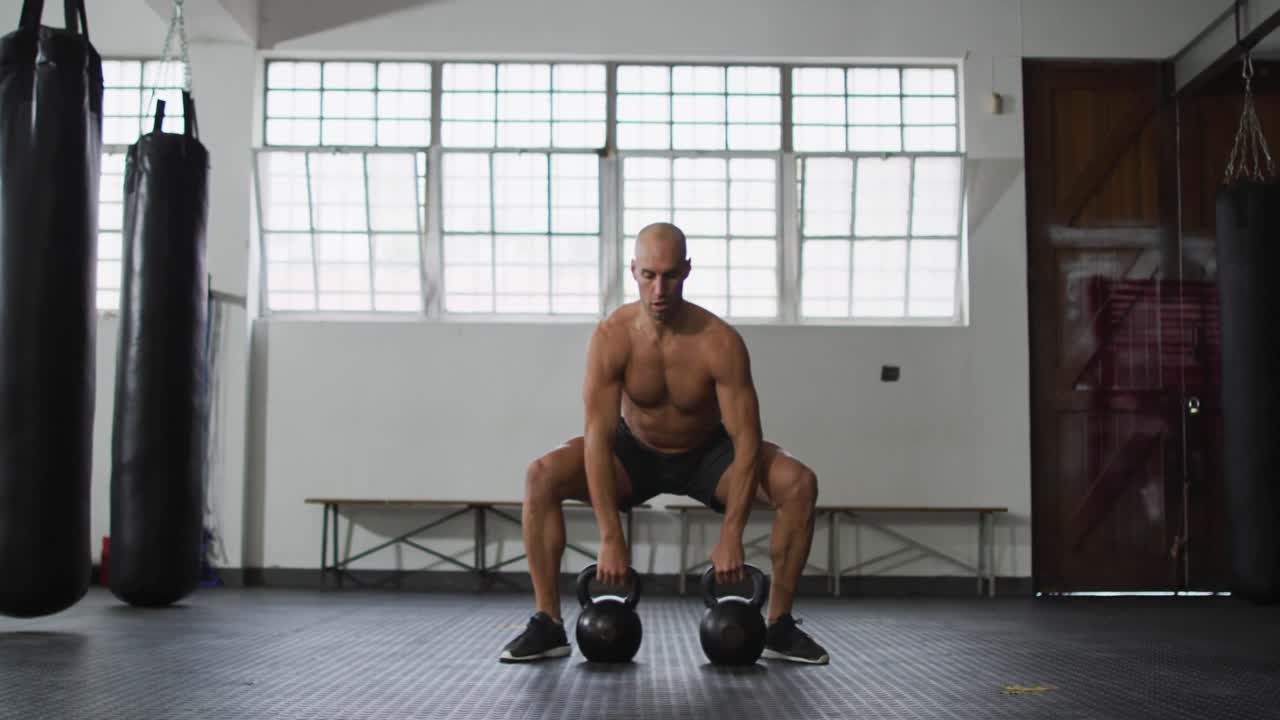 hombre caucásico en forma trabajando con campanas de hervidor en el gimnasio