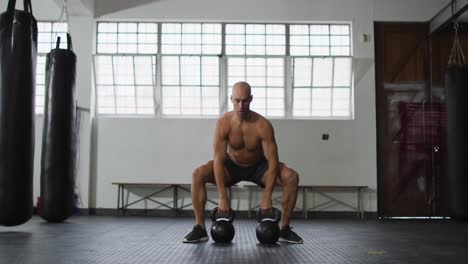 fit caucasian man working out with kettle bells at the gym