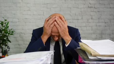 an over worked and stressed businessman with a pile of paperwork in stacks on a desk