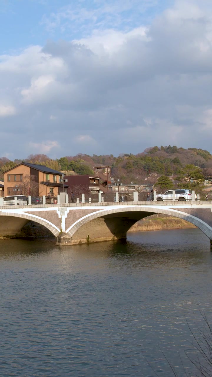 Inquadratura ampia statica di un ponte in pietra a più arcate su un fiume a Kanazawa, Giappone