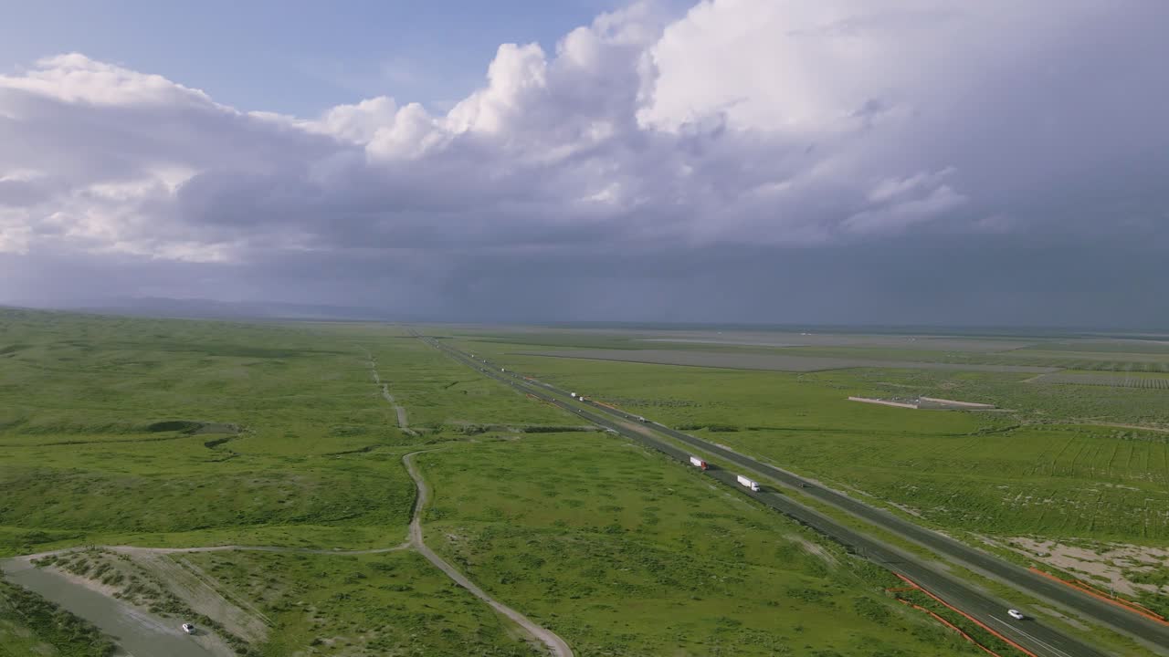 беспилотник медленно скользит и кружит, захватывая зеленые калифорнийские поля и шоссе 5, под надвигающимся величием дождевых тяжелых облаков.