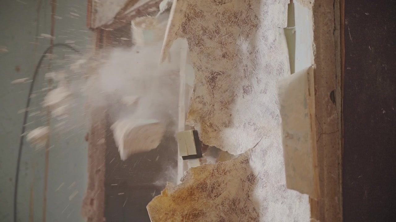 Heavy impact sends plaster fragments and dust through abandoned renovation space