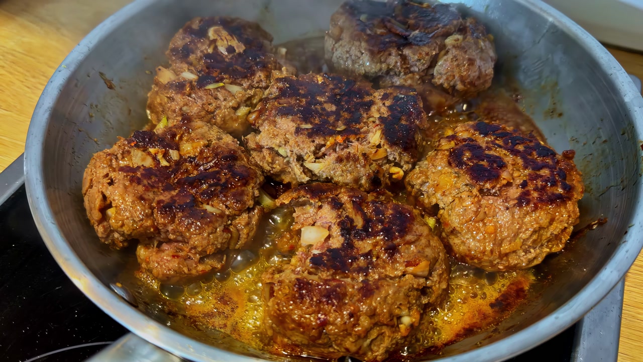 Ground beef burgers sizzling on stovetop, close up view