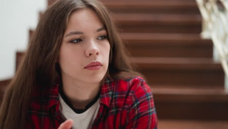 upset woman sits alone on staircase closeup. lady in casual clothes expresses negative feelings in residential building. woman recalls traumatic memories