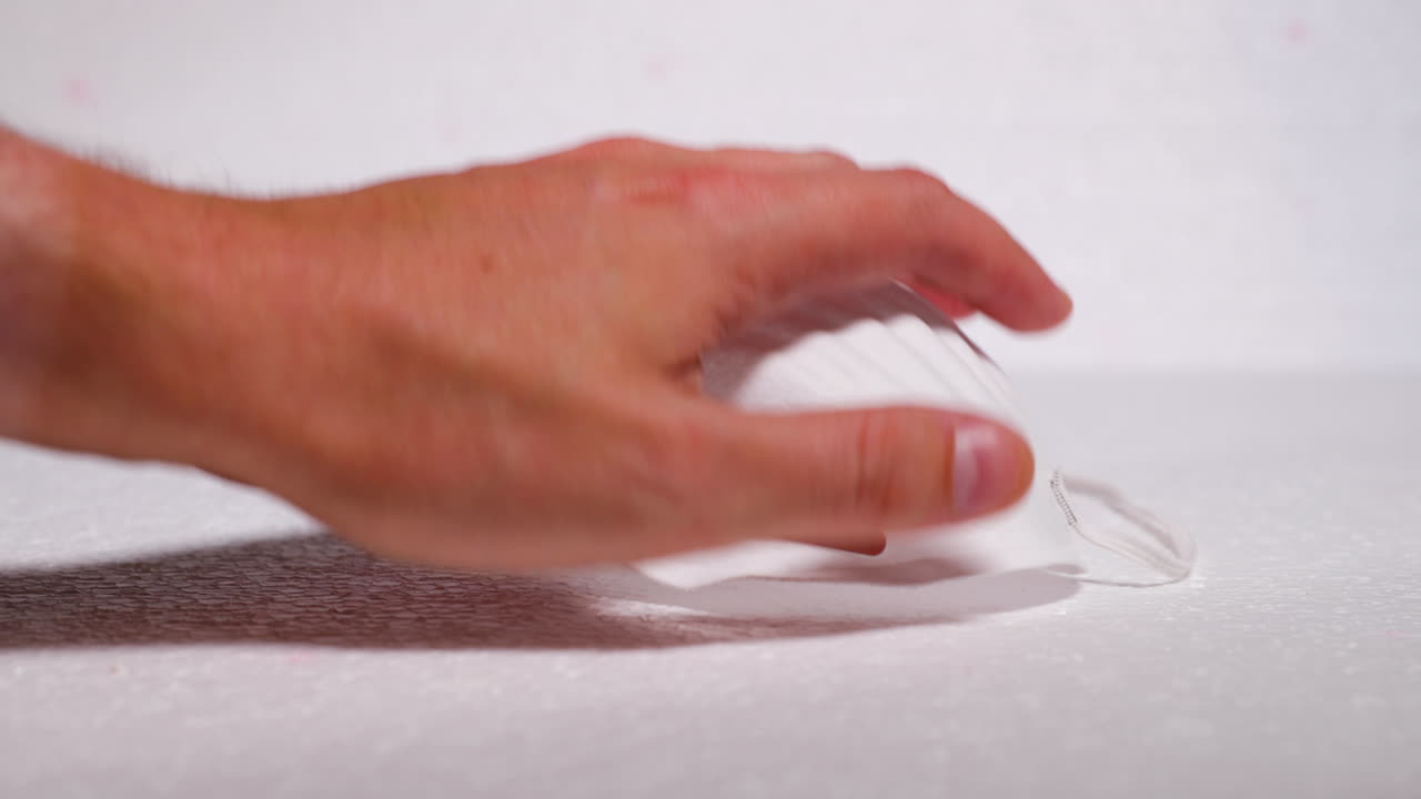 Hand putting protective facial white mask mask against threat like corona covid-19 virus on white backing protecting mouth and nose on plate capture in 4k 60fps