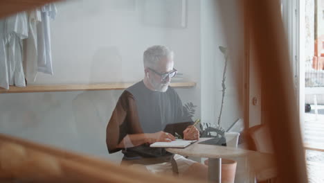 cafe manager making notes in earphones. stylish senior freelancer working tablet