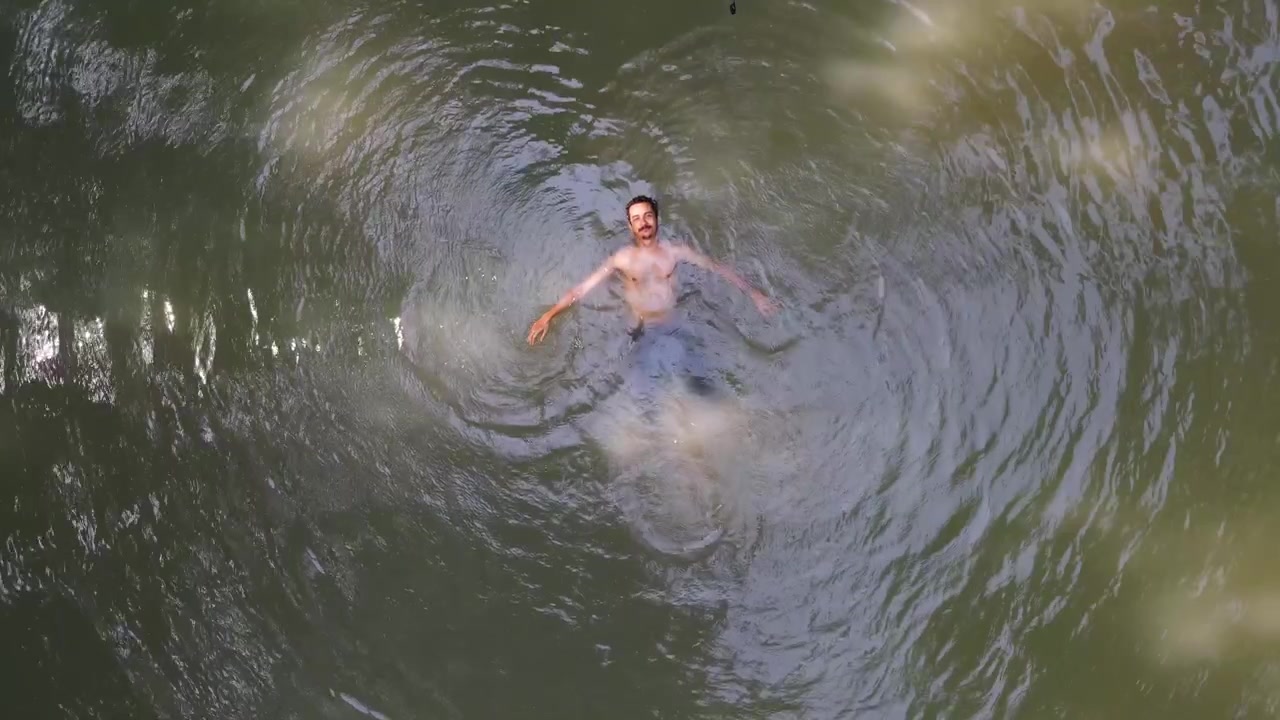 A man floating on water. Enjoying relaxing calmness. Meditation vibe. Top down ascending shot