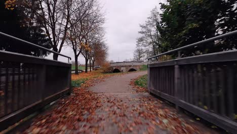 a drone flies low over the ground crossing a bridge