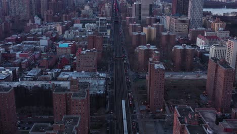 backward drone flight over elevated train tracks of harlem, new york city just after sunrise