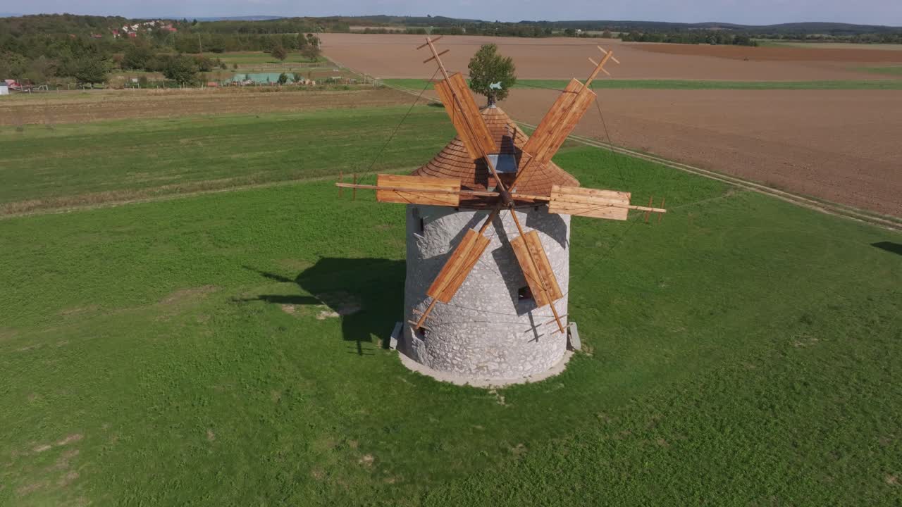 Molino de viento girando suavemente sobre tranquilos campos de pueblo, Hungría