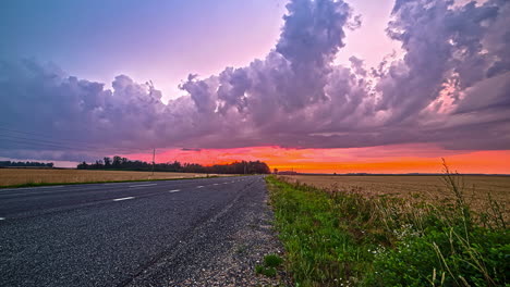 timelapse shot of massive white clouds passing by over highway with farmlands on both sides