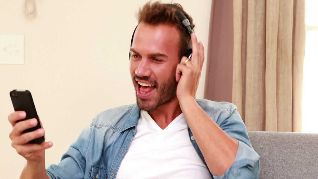 hombre guapo escuchando música, cantando y usando un teléfono inteligente