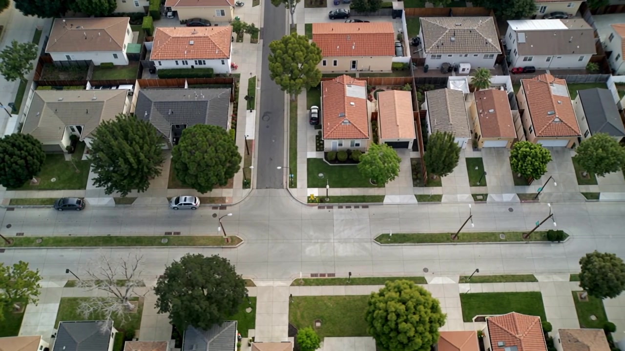 Lançando drone inspecionando um cruzamento de quatro vias em um subúrbio, avançando e mostrando carros estacionados e árvores