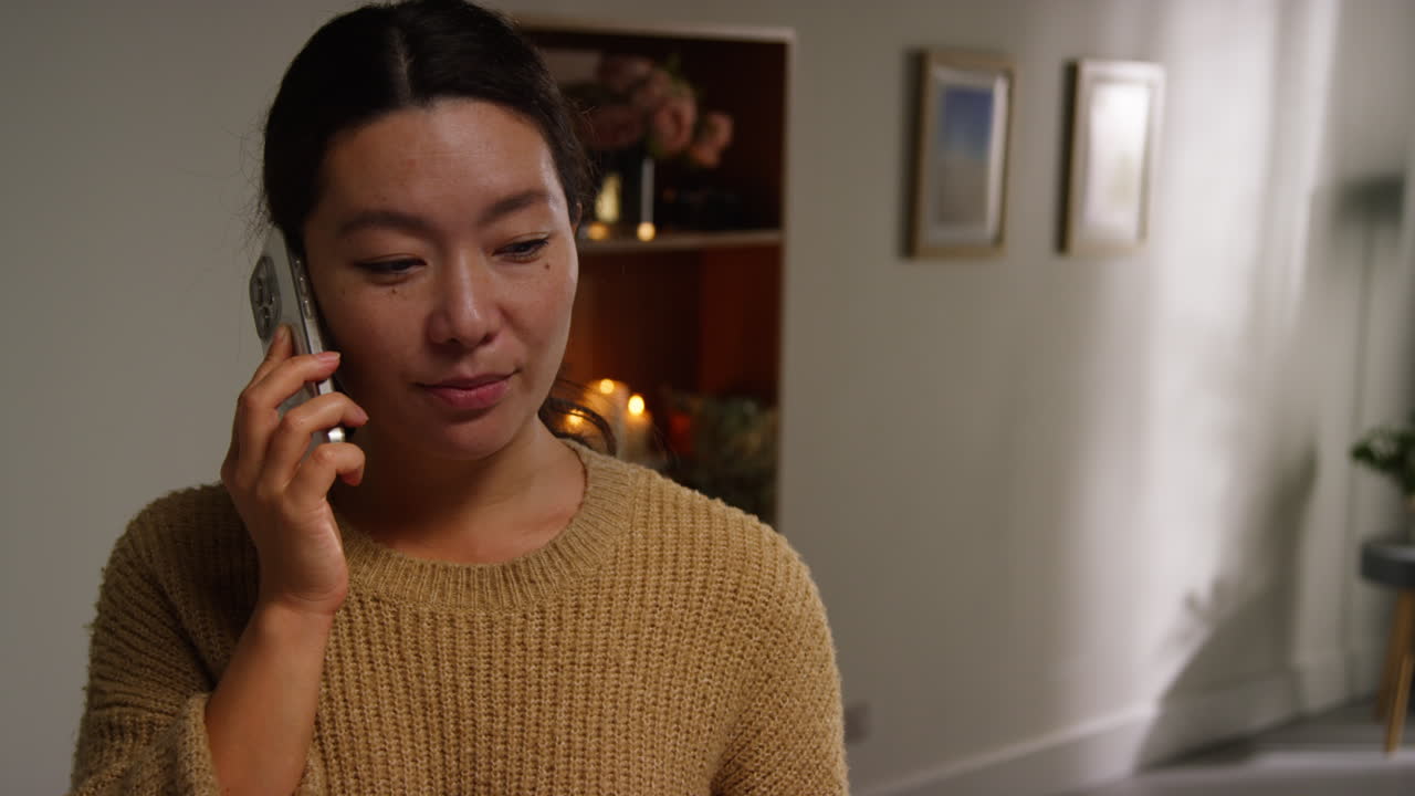 가정에서 주방에서 휴대전화로 대화하는 여성 건강한 식사를 위한 재료를 준비하고 공중에 노란 고추를 던지고 있습니다.