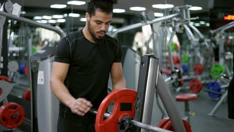 Hombre-Culturista-Atlético-Entrena-En-El-Gimnasio-Con-Levantamiento-De-Pesas,-Agregando-Pesas