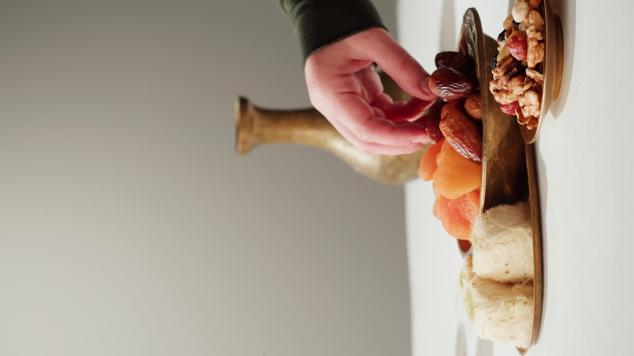 Hand picking dates from a tray of Middle Eastern sweets