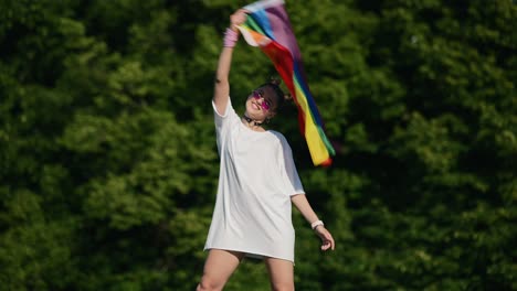 woman holding a rainbow flag in a park