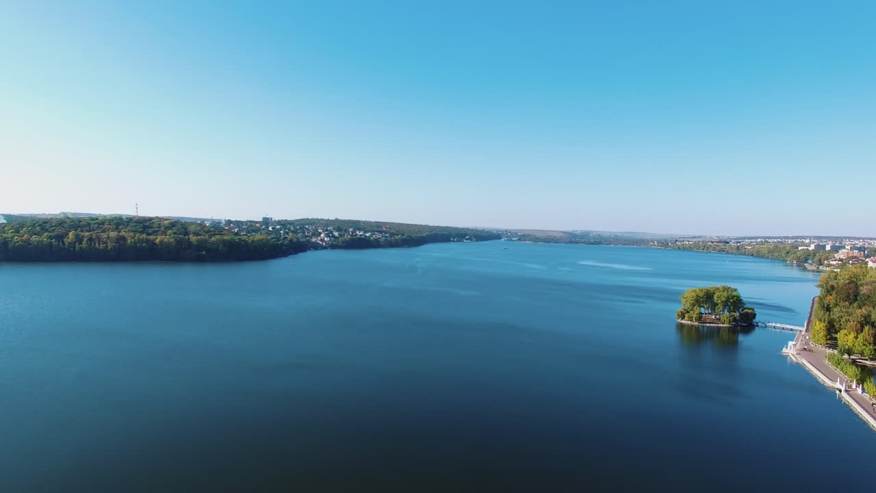 Amazing view of a blue river near the city. Wide calm river under the blue sky on the town landscape in summer. Aerial view.