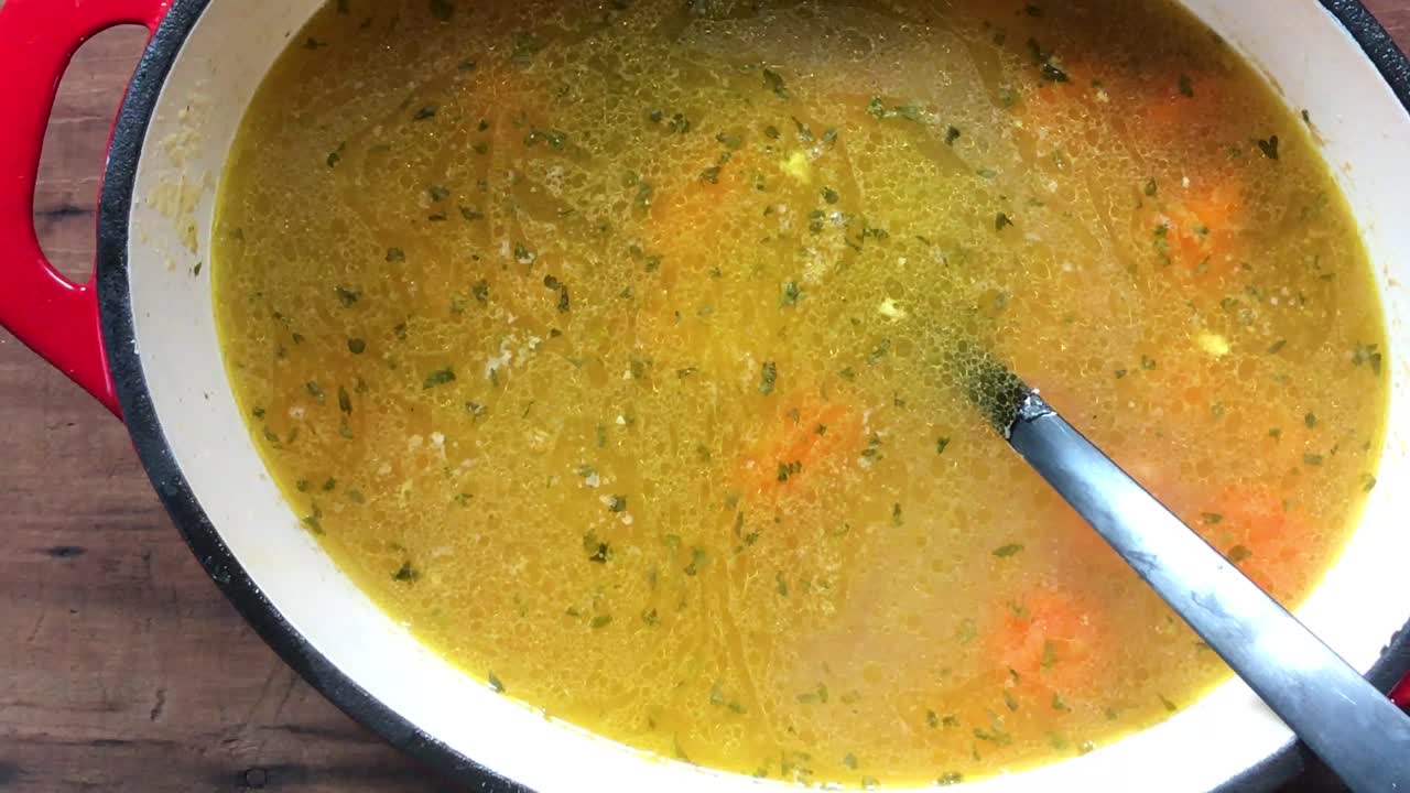 primer plano de agitación de una gran olla de hierro fundido de pollo casero y albóndigas con zanahorias con cuchara de cucharón