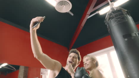 Boxing-trainer-doing-selfie-photo-with-woman-boxer-on-punching-bag-background.