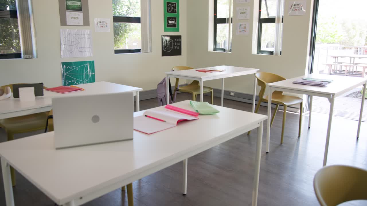 A câmera avança, revelando um laptop prateado e um caderno rosa para destacar a área de estudo.