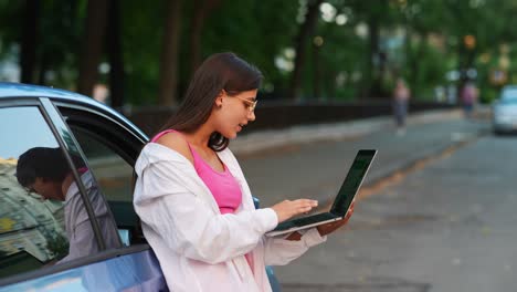 mujer joven trabajando en una computadora portátil afuera de un coche