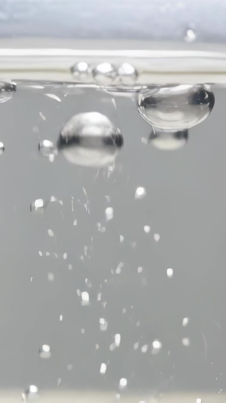Video verticale: Rilascio del flusso, bolle che salgono in una vasca da laboratorio, che si deformano in superficie, formando uno spruzzo.