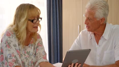 una pareja de adultos felices mirando una tableta digital y discutiendo