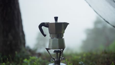 making a hot coffee using portable coffee maker pot in a campsite