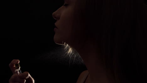 mujer rociando perfume en su cuello