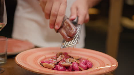 hands of the waiter grating bottarga over the dumplings gourmet dish