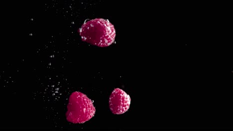 raspberries falling into water super slowmotion, black background, lots of air bubbles, 4k240fps