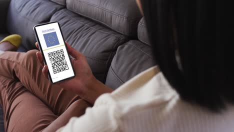 mujer en casa con un teléfono inteligente con certificado de vacunación contra la covid, bandera de la ue y código qr en la pantalla
