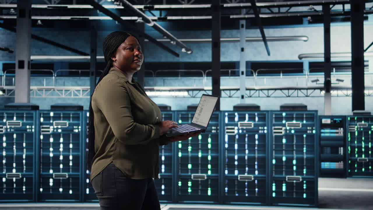 Software developer in data center using laptop to deploy new server architecture