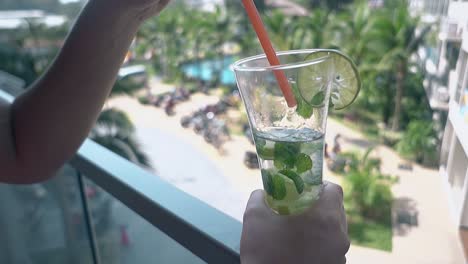 lady stands on terrace with mojito against hotel territory