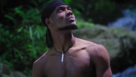 Muscular-dark-toned-man-in-a-bandana-looks-up-on-a-sunny-day