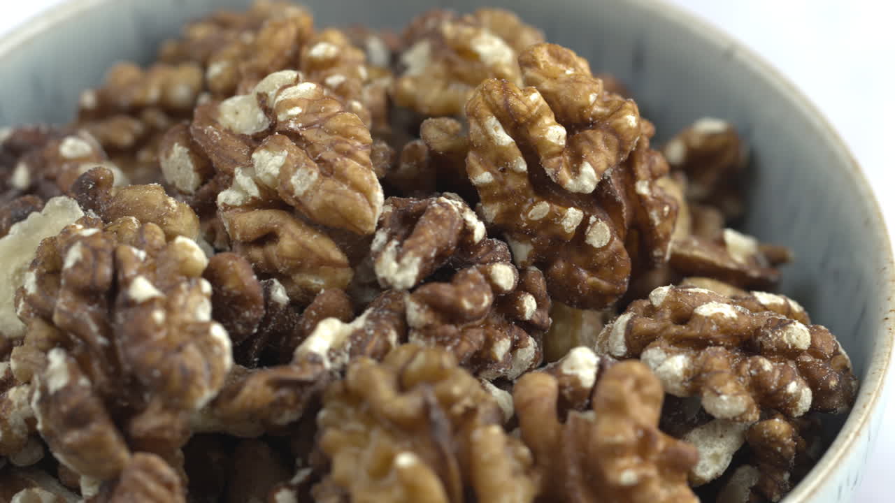 Pan Across A Bowl Of Walnuts.Nuts And Food On White Background. Protein Plant Based Raw Vegan Food. Health And Vegetarian Foods. Healthy Breakfast Ingredients. Macro 4K Shot